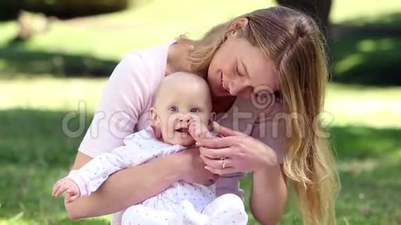 快乐的妈妈抱着她的宝贝女儿在公园里视频的预览图