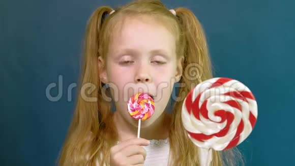 蓝色背景上有棒棒糖的小女孩特写肖像视频的预览图