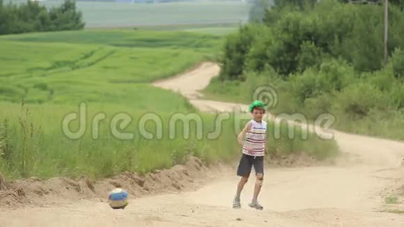 男孩在沙地公路户外踢足球视频的预览图