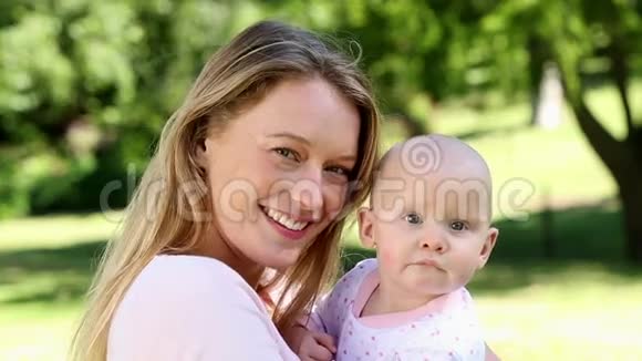 快乐的妈妈抱着她的宝贝女儿在公园里视频的预览图