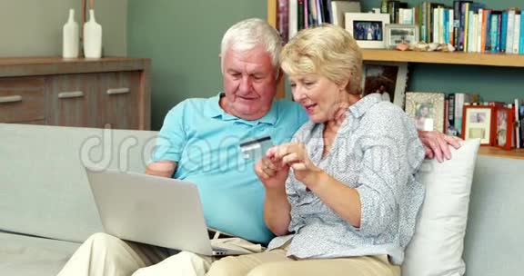年长夫妇使用笔记本电脑持有信用卡视频的预览图