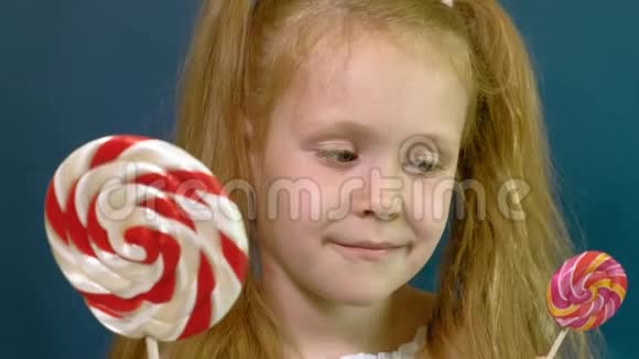 蓝色背景上有棒棒糖的小女孩特写肖像视频的预览图