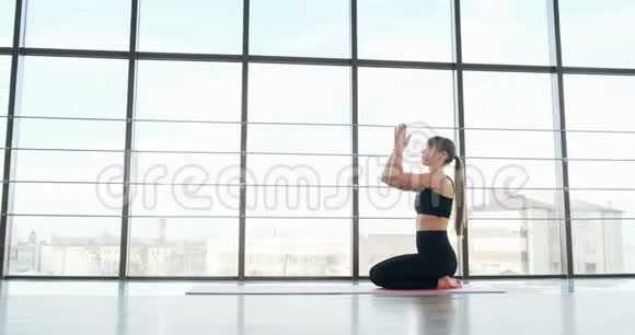 漂亮的年轻女人在有大窗户的房间里做瑜伽锻炼有魅力的女性在她的身体里工作视频的预览图