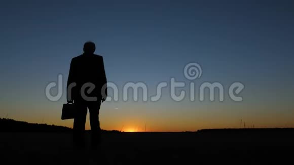 剪影男商人穿着商务服手里拿着一个公文包夕阳西下视频的预览图
