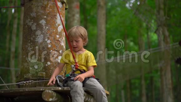 在森林探险公园的一条路线上一个穿着安全装备的小男孩被拍到了超慢镜头室外娱乐中心视频的预览图