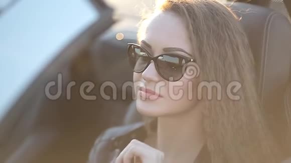 穿着皮夹克的长发戴着墨镜的皮裤的漂亮女孩坐在驾驶室里视频的预览图