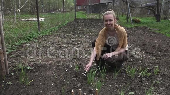 年轻漂亮的女人照看花园里的植物视频的预览图