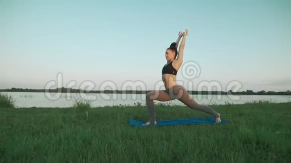 年轻女孩穿着运动服早上在湖里和科普空间做瑜伽视频的预览图