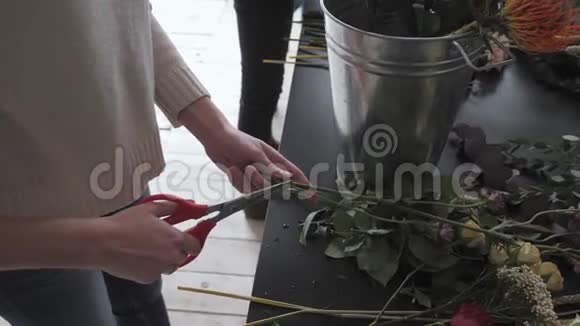主班女花艺师在工作与束花女孩制作各种秋花的花束商务视频的预览图
