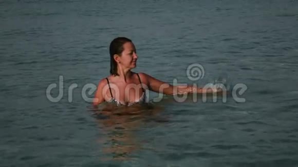 在美丽的日出上玩海水的女人视频的预览图