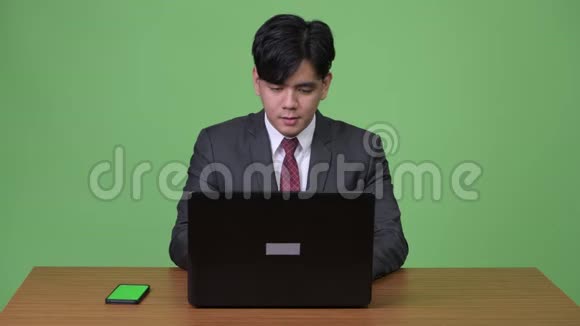 年轻英俊的亚洲商人在绿色背景下工作视频的预览图