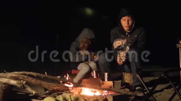 孩子们微笑孩子们喝茶青少年坐在火炉旁的生活方式夜晚篝火旅行徒步旅行冒险露营视频的预览图
