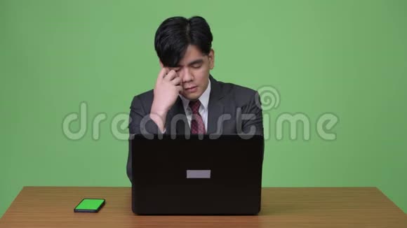 年轻英俊的亚洲商人在绿色背景下工作视频的预览图