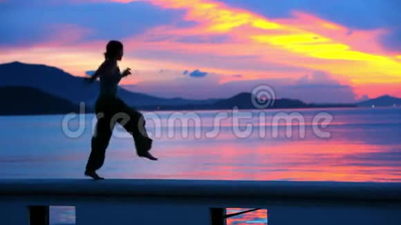 在萨梅岛的海上日落中跳跃的快乐女人视频的预览图