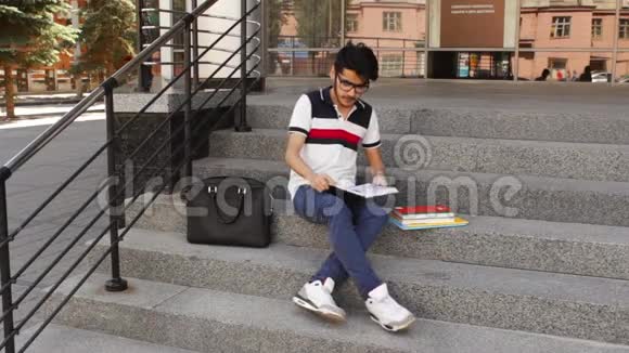 亚洲男学生坐在楼梯上看书视频的预览图