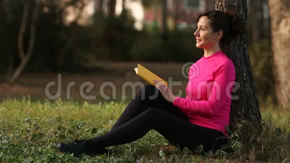 年轻女子在绿色公园看书视频的预览图