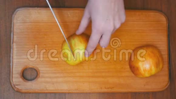 女人的手与刀切苹果在木制厨房板在家庭厨房视频的预览图