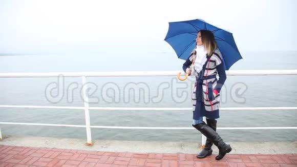 带着雨伞的女人在码头上放松海洋视频的预览图