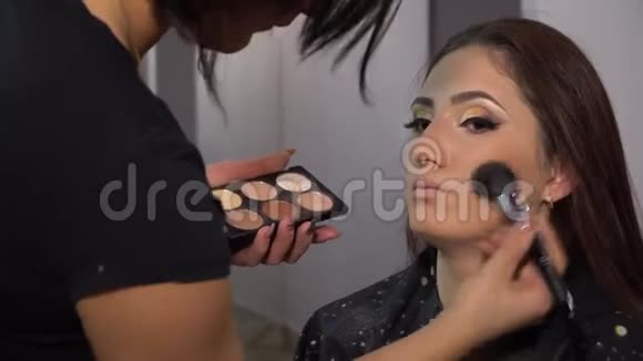 美容院年轻漂亮的女孩模特坐在椅子上化妆师给女孩化妆布鲁奈特的美丽视频的预览图