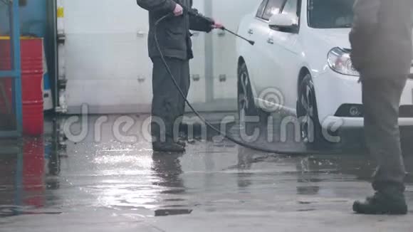 汽车服务部门的洗车工正在用水管把一辆汽车冲洗干净视频的预览图