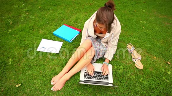 学生拿着笔记本电脑坐在草地上视频的预览图