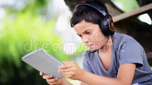 儿童听音乐用耳机在室外电脑上播放视频的预览图