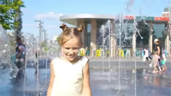 在炎热的晴天小可爱的女孩在街头喷泉里玩得很开心视频的预览图