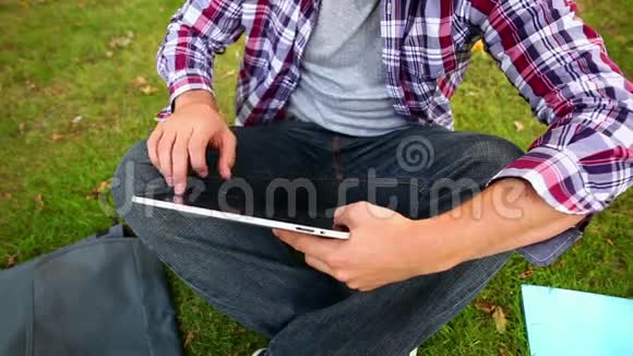 学生用他的平板电脑坐在草地上视频的预览图