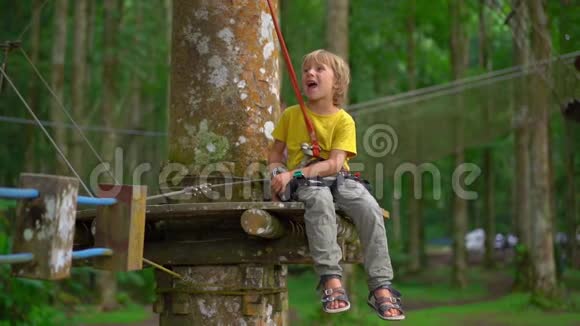 在森林探险公园的一条路线上一个穿着安全装备的小男孩被拍到了超慢镜头室外娱乐中心视频的预览图