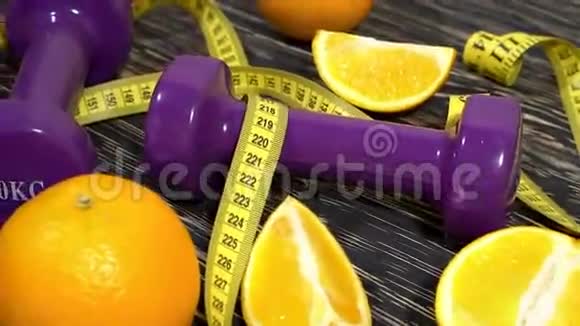 橘子果汁哑铃和木制背景上的测量带视频的预览图