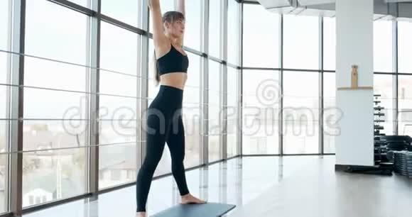 漂亮的年轻女人在有大窗户的房间里做瑜伽锻炼有魅力的女性在她的身体里工作视频的预览图