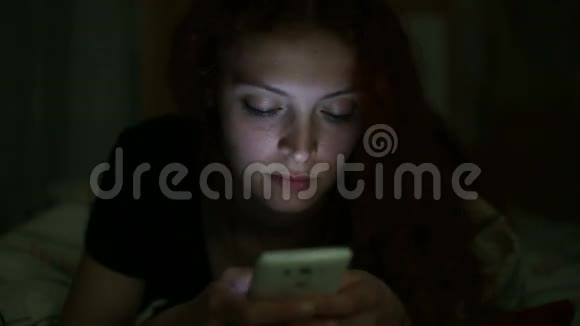 晚上一位使用智能手机的年轻女性躺在家里视频的预览图