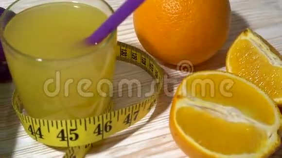 橘子果汁哑铃和木制背景上的测量带视频的预览图