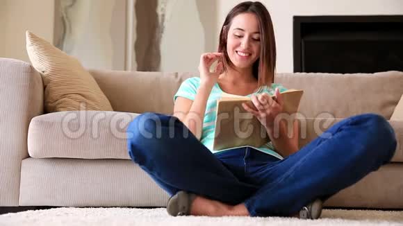 漂亮的黑发女人在地毯上放松阅读视频的预览图