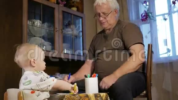 祖父和他孙子的孩子在纸上画记号这个男孩仔细地看着并帮忙微笑和惊讶这就是视频的预览图