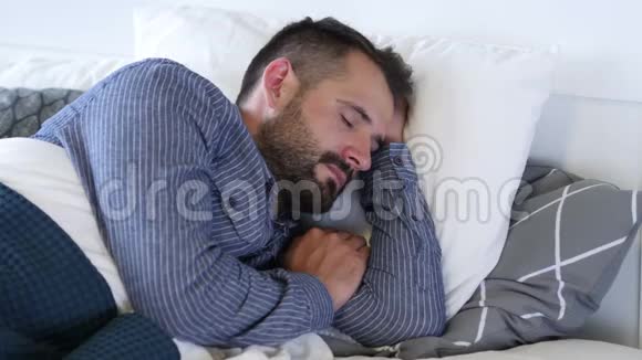 年轻的胡须男睡在床上视频的预览图