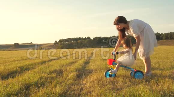 妈妈教女儿骑自行车妈妈和她的小女儿玩一个小孩子学会骑自行车概念视频的预览图