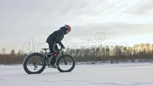 专业的极限运动员骑着一辆肥胖的自行车在户外骑自行车的人在冬天骑在雪冰上人类视频的预览图