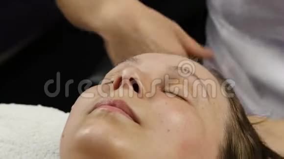 在水疗中心接受头部按摩的女人做面部按摩的女医生4K视频的预览图