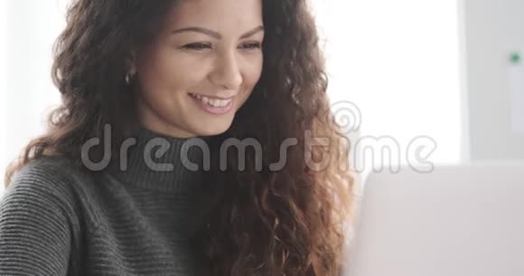 快乐的女人在办公室用笔记本电脑视频的预览图