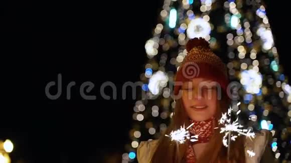 一个女孩拿着孟加拉灯对着圣诞树视频的预览图