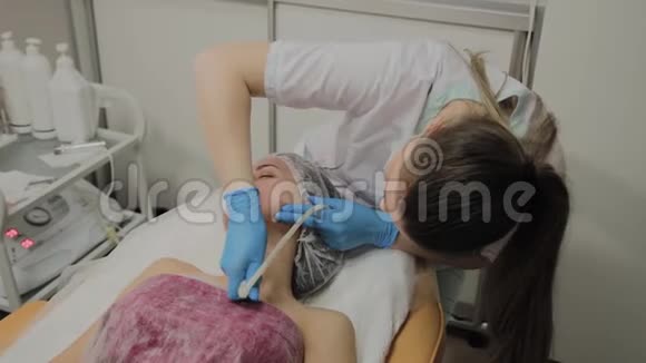 一位专业的美容师让一个女人在美容院用吸尘器清洁脸部宇宙学创新视频的预览图
