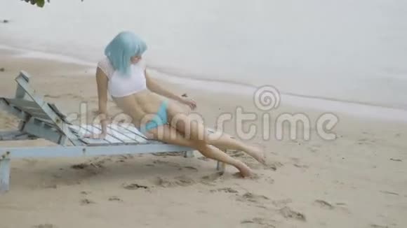 海滩上穿比基尼和蓝色假发的女人的创意外观视频的预览图
