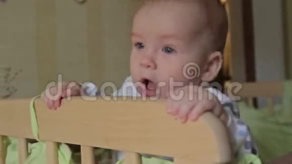可爱的小男孩站在婴儿床上视频的预览图