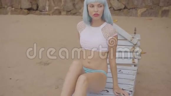 海滩上穿比基尼和蓝色假发的女人的创意外观视频的预览图