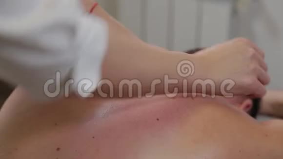 专业女性按摩师在男人的背上做按摩在美容院按摩视频的预览图
