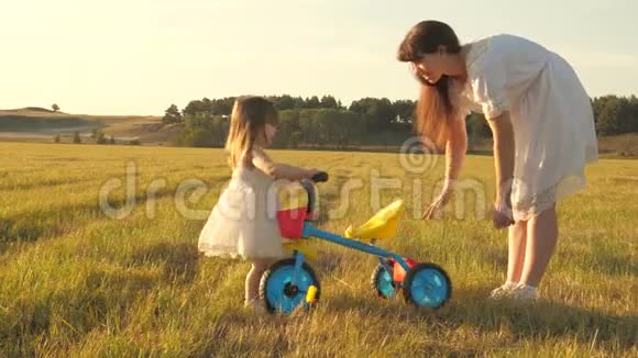 妈妈教女儿骑自行车妈妈和她的小女儿玩一个小孩子学会骑自行车概念视频的预览图