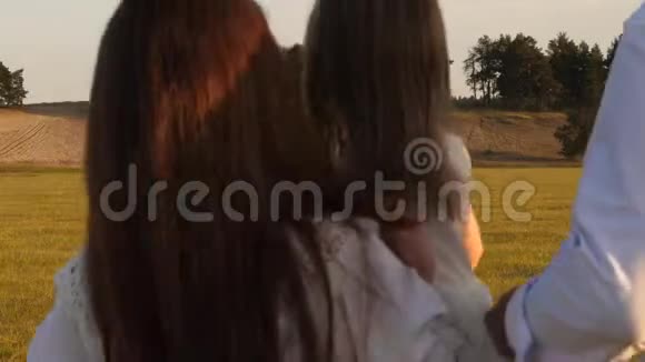 妈妈爸爸和小女儿在田野里散步快乐的年轻家庭幸福家庭的概念幸福的概念视频的预览图
