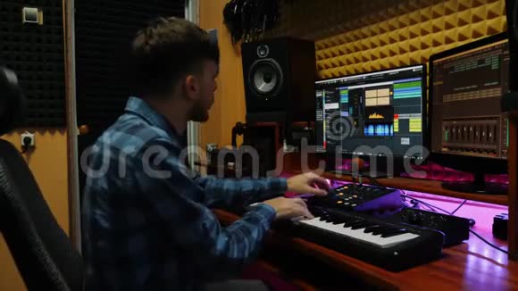 男音乐家作曲家弹钢琴MIDI键盘音响工程师在录音室工作配备显示器和均衡器视频的预览图