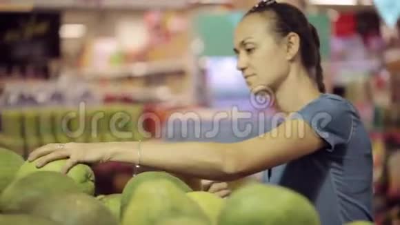 年轻的母亲和小女儿在超市挑选水果视频的预览图